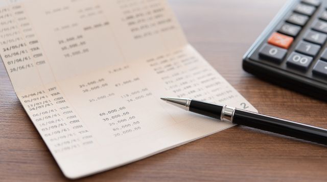 Wyciąg z rachunku bankowego obok długopis i kalkulator