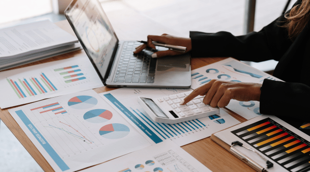 Wyliczanie ile podatków się zapłaci i jak uniknąć podwójnego opodatkowania, w biurze robi to pani przy komputerze i papierach